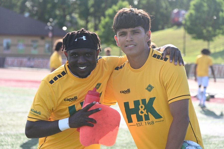 Two RUAC players in gold warm-up jerseys with a front-of-shirt logo