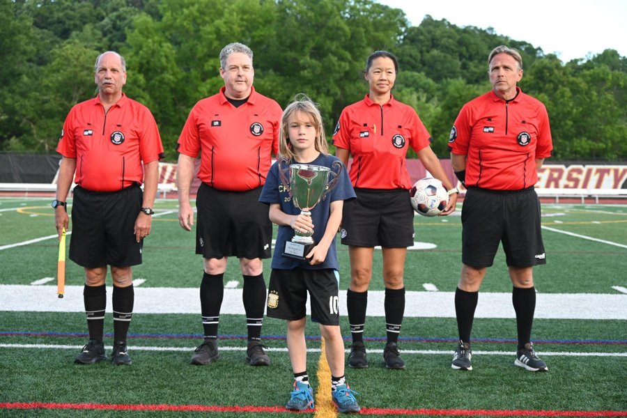 The match officials lined up on the field before an RUAC home match