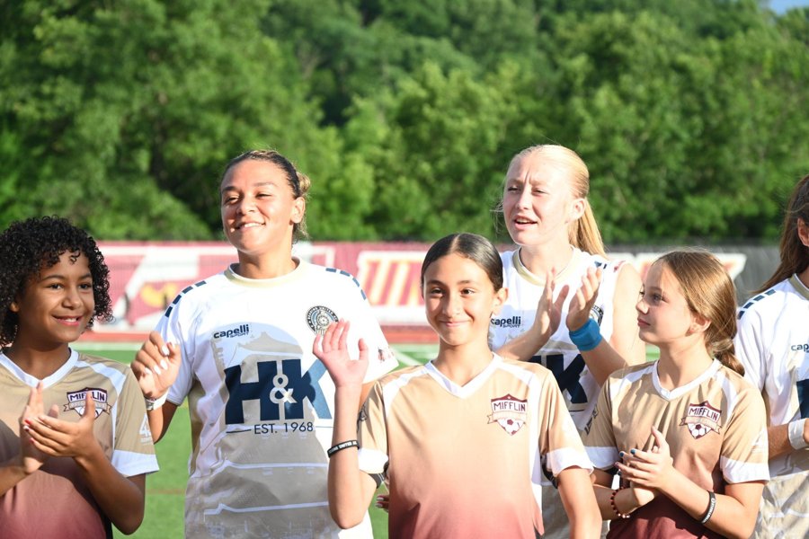 RUAC women&rsquo;s players with young fans on the field at a home match