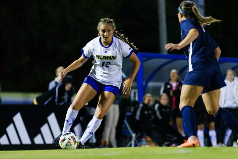 Maggie Holloway, in white No. 12, dribbles for the University of Delaware
